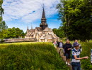 Ett gäng vandrar uppför en backe. I bakgrunden syns en stor stenkyrka.