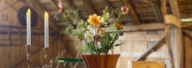 Attareds Blomster gårdsbutik, sommarcafe på loge. Bord med tända ljus och blomsterarrangemang.